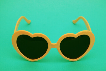 Sunglasses with an orange frame on a green paper background.