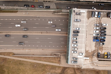 Drone photography of highway going in a tunnel under office space and parking place on a roof.