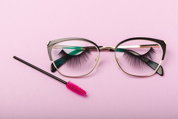 Composition with false eyelashes and glasses, mascara and eyelash brushes, eyelash curlers on a pink background. Makeup artist tools. Beauty concept. Compose. Place for text. Place to copy. Flatley. 