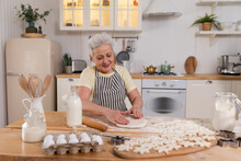 Happy Senior Woman Cooking In Kitchen. Stylish Older Mature Gray Haired Lady Grandmother Knead Dough Bake Cookies. Old Grandma Cook Homemade Food. Household Housewife Housework Concept