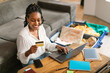 © Prostock-studio - Happy african american woman using credit card and laptop, booking abroad trip, surfing online travel agency website