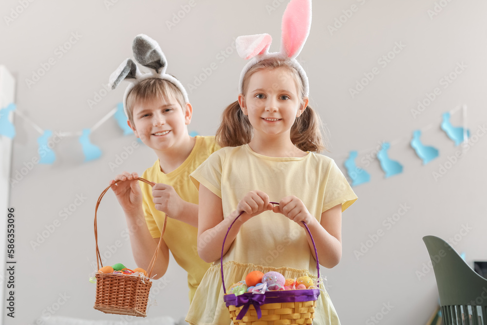 Little children with bunny ears and baskets of Easter eggs at home