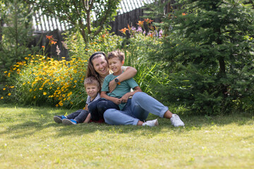 A young woman is lying on the grass with her two sons and they are laughing