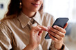 © Seventyfour - Close up of smiling young woman holding smartphone and tapping screen, copy space