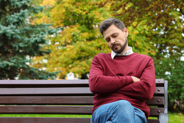 Canvas Print - Tired man sleeping on bench in beautiful green park. Space for text