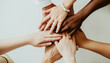 © Studio Multiverse - Close-up top view of young diverse business people putting their hands together. Stack of hands. Unity and teamwork concept.Generative ai.