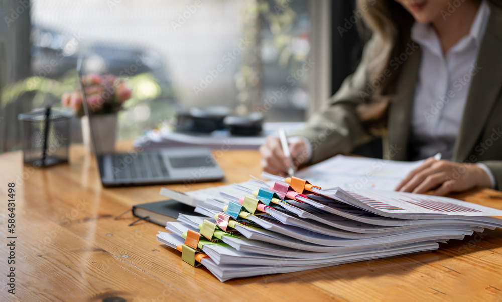 Business Documents concept : Businesswoman working in Stacks of paper files for searching and checking unfinished document achieves on folders papers.