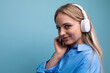 © Ivan Traimak - horizontal photo of an attractive girl in wireless large headphones listening with pleasure to music from a playlist on a blue background