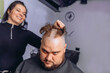 © Semachkovsky  - Hairdresser girl shaves hair from head of adult man completely. Getting rid of the hair on the head. Provision of services in a hairdressing salon.