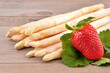 Fresh white asparagus and red strawberry on wooden background. 