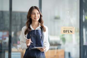 Asian female worker or barista standing smiling and holding the tablet in front of cafe working woman small business owner in food and beverage.