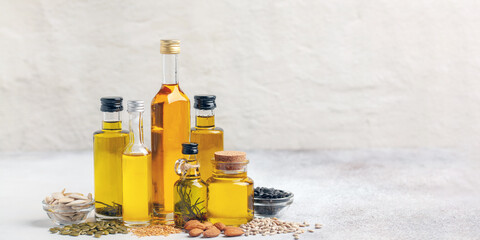 Various vegetable and nut oil in bottles on a bright background.