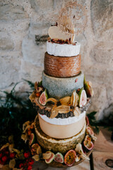 A well highly decorated cheese cake in front of an antique old wall with a detail card at side of the cake