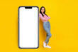 Full size photo of cute sweet cheerful girl dressed striped top jeans recline on banner empty space isolated on yellow color background