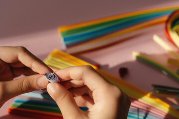 Paper and quilling tools on a pink background with hands and space for text and design. For design. Minimalism.