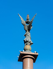 Angel With Wings Stands On Ball At Top Of Column With Sailboat In Raised Hands. Column "Sea Glory Of Russia" On Embankment Of Admiral Serebryakov. Close-up. Novorossiysk, Russia - November 5, 2021