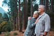 © Nina/peopleimages.com - Hug, hiking and senior couple in forest, workout and quality time outdoor, happiness and wellness. Romance, mature man and old woman in woods, walking and fitness for healthy lifestyle and nature