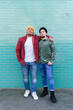 © VISTA by Westend61 - Brothers standing together in front of turquoise brick wall