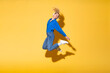 © VISTA by Westend61 - Carefree woman jumping in joy against yellow background