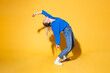 © VISTA by Westend61 - Woman with hand raised dancing against yellow background