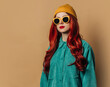 © VISTA by Westend61 - Redhead woman wearing knit hat and sunglasses against brown background