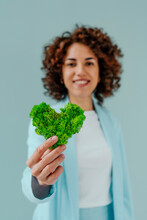 Woman Holding Green Heart Shaped Moss Against Blue Background