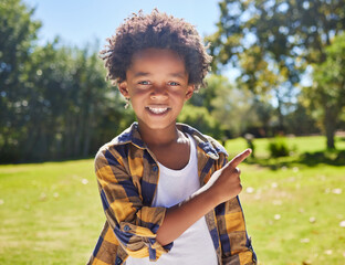 Wall Mural - African boy, pointing and park portrait with smile, happiness or playful in outdoor sunshine. Young black child, point and hand gesture on grass in summer with excited face, happy and freedom to play