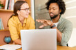 © Vadim Pastuh - Selective focus at the laptop, two colleagues have discussion, conversation sitting side by side in modern open space on background, male mentor explaining something to colleague, brainstorming