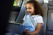 © Nina/peopleimages.com - Child in car, tablet and video on road trip with seatbelt for safety and device to play educational online game. Technology, internet browsing and travel, happy girl on backseat for drive or carpool.