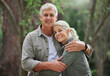© Nina/peopleimages.com - Hug, hiking and portrait of senior couple with smile on adventure in forest, woods and mountain for exercise. Fitness, travel and happy elderly man and woman in retirement, holiday and relax on hike