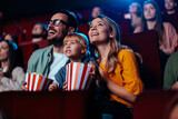 Fototapeta Tulipany - Joyful family watching movie in cinema.