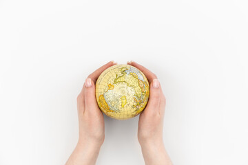 Earth globe in female hands on a white background isolated, top view, Earth Day concept, care for the planet.