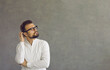 © Studio Romantic - Puzzled and confused Caucasian man scratches the back of his head thinking about something important. Pensive man on a gray concrete background looks at the free space for text. Banner Advertising.