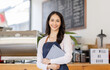 © David - Startup successful small business owner sme beauty girl stand with tablet smartphone in coffee shop restaurant. Portrait of asian tan woman barista cafe owner. SME entrepreneur seller business concept