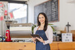 © David - Startup successful small business owner sme beauty girl stand with tablet smartphone in coffee shop restaurant. Portrait of asian tan woman barista cafe owner. SME entrepreneur seller business concept