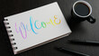 © treenabeena - WELCOME colorful hand lettering in notebook with cup of coffee and pens on black wooden desk