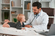 © standret - With stethoscope. Doctor with little baby is working in the cabinet