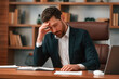 © standret - Tired, feeling bad. Businessman in formal clothes is working indoors