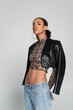 © LIGHTFIELD STUDIOS - stylish african american model in crop top with animal print and black leather jacket posing isolated on grey.