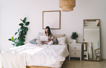 Canvas Print - Woman sitting with laptop on bed at home