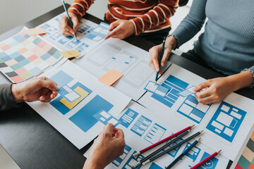 Close up ux developer and ui designer brainstorming about mobile app interface wireframe design on table with customer breif and color code at modern office.Creative digital development agency