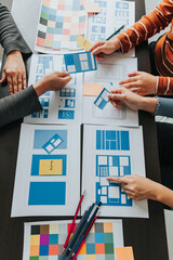 Close up ux developer and ui designer brainstorming about mobile app interface wireframe design on table with customer breif and color code at modern office.Creative digital development agency