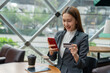 © StockPhotoRepublic - Young asian businesswoman beautiful female lady sitting in a cafe and confidently doing online payment transaction using her mobile phone digital banking app and credit card