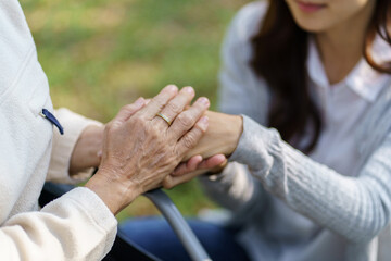 Family relationship Asian senior woman in wheelchair with happy daughter holding caregiver for a hand while spending time together