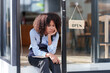 © amnaj - Female shopkeeper sitting stressed out at the store entrance frustrated by the economic impact.