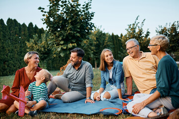 Wall Mural - Happy multigeneration family talks while relaxing in backyard.