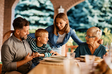 Wall Mural - Happy extended family communicating at dining table on terrace.