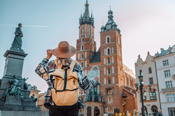 back view of traveller woman walking on old market square in krakow holding tourist map. travel and 