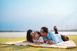 © Kiattisak - Happy family in the park on weekend. family enjoying together in the meadow with river Parents hold the daughter.health life insurance plan concept.