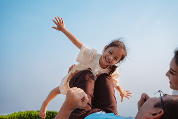 Wall Mural - Happy family in the park on weekend. family enjoying together in the meadow with river Parents hold the daughter.health life insurance plan concept.